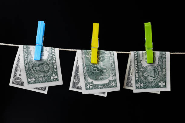 One and two dollar banknotes fastened with clothespins are dried on clotheslines on a dark background