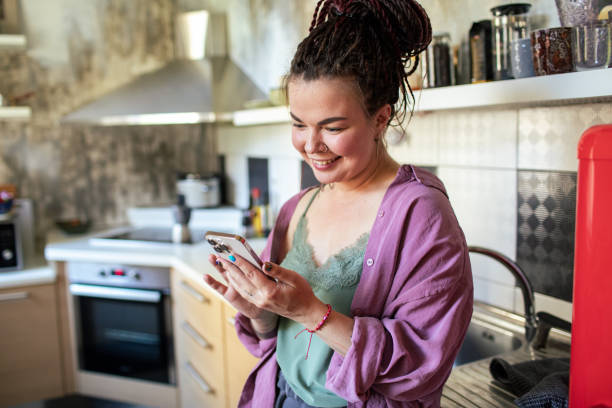 istock Young adult woman using a smart phone in a kitchen 1484506564