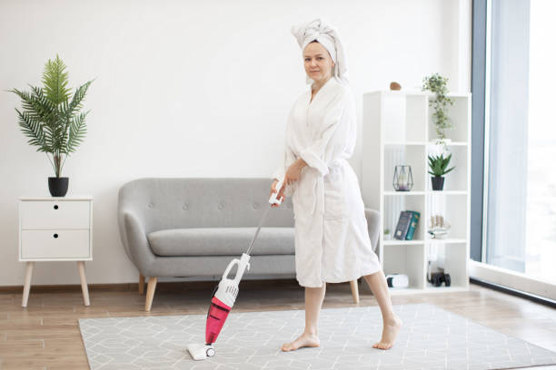 istock Lady in robe cleaning living room with wireless vacuum 1484514588