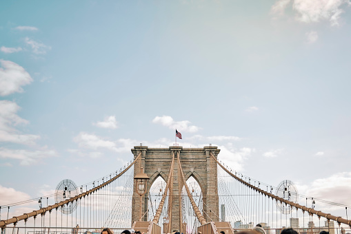 The famous brooklyn bridge in New York, USA. Suspension bridge column and cables against blue sky.