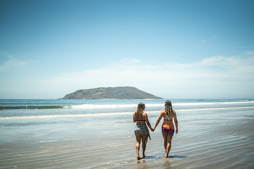 Lesbian couple taking a walk by the sea holding hands