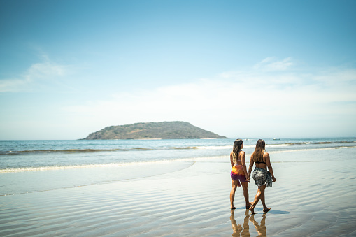 Traveler female friends taking a walk by the sea
