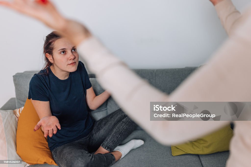 Mother Dealing with Disobedient Daughter in Living Room A mother tries to deal with her disobedient teenage daughter in the living room, with both parties visibly upset Conflict Stock Photo