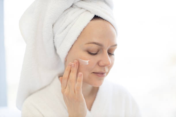 istock Lady using facial cream after shower on bright background 1484543346