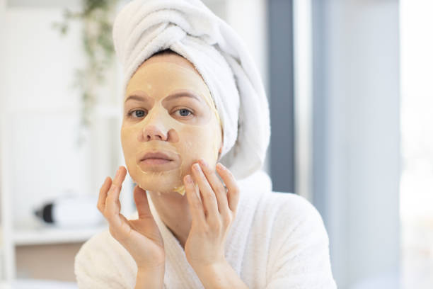 istock Woman touching cosmetic mask on face in home interior 1484543414
