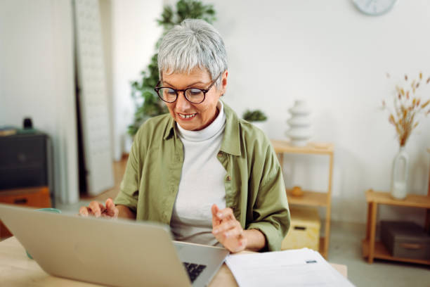 istock Smiling senior woman using laptop at home 1484555160