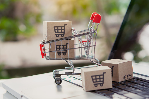 Shopping online. Cardboard box with a shopping cart logo in a trolley on laptop keyboard. Shopping service on The online web. offers home delivery