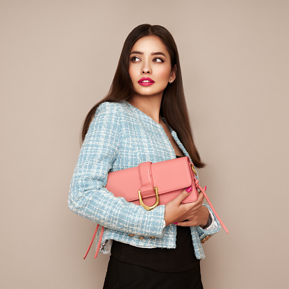 Young brunette woman in blue jacket. Model posing in a business suit. Girl  with pink handbag. Fashion photo