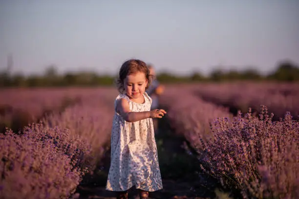 Photo of Playful cute boy girl are playing in rows of lavender purple field at sunset. Small couple. Allergy