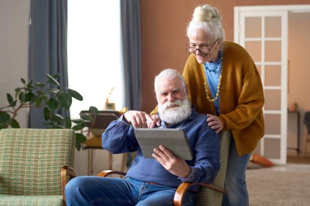 タブレットpcでビデオ通話をしている祖父母 - senior adult couple computer retirement ストックフォトと画像
