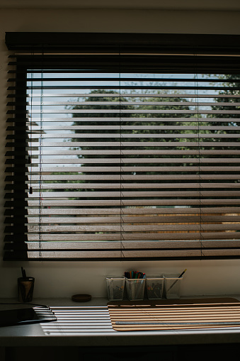 Sun shining through high quality wooden blinds, into a home office space