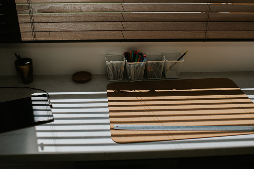 Sun shining through high quality wooden blinds, into a home office space