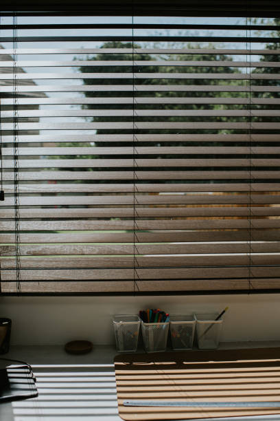 Sun shining through high quality wooden blinds, into a home office space