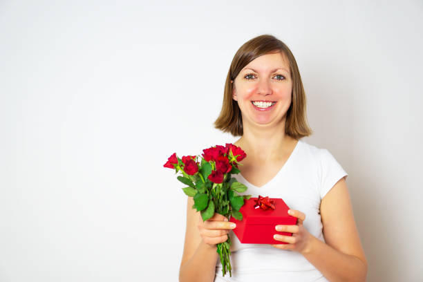 an Asian woman as she reveals a boxed gift, her expression radiating excitement against a pristine white backdrop