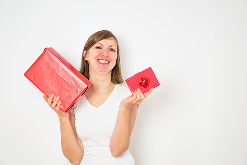 Happy pretty young woman in a white shirt holding two red gift boxes on the white background. High quality photo.