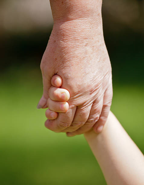 istock Grandma holding grandchilds hand 148458446