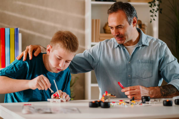 istock Father watching his son assembling a toy while holding his hand on his shoulder. 1484586128