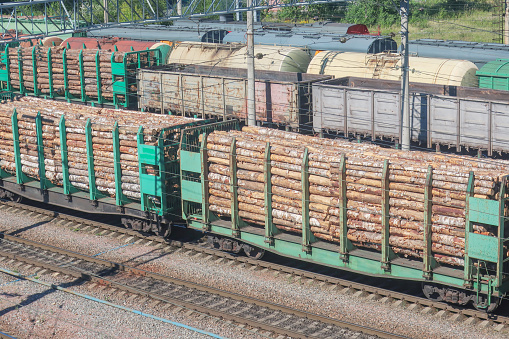 congestion of freight trains at the station with freight wagons loaded with timber at the station