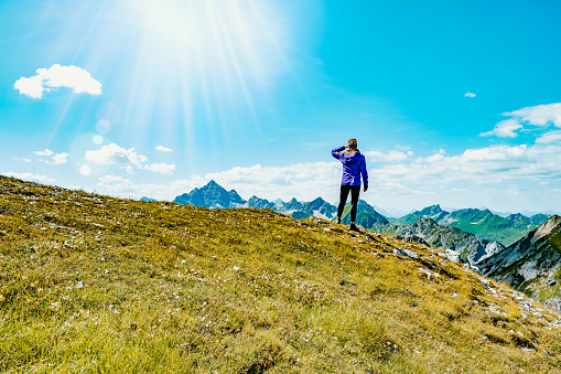 Description: Hiker enjoys fantastic view from the Kastenkopf at noon. Schrecksee, Hinterstein, Allgäu High Alps, Bavaria, Germany.