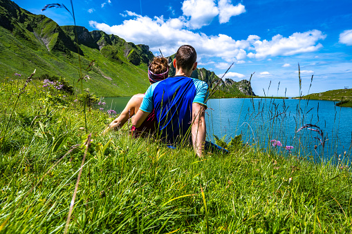 Description: Couple enjoys scenery at beautiful turquoise mountain lake in the afternoon. Schrecksee, Hinterstein, Allgäu High Alps, Bavaria, Germany.