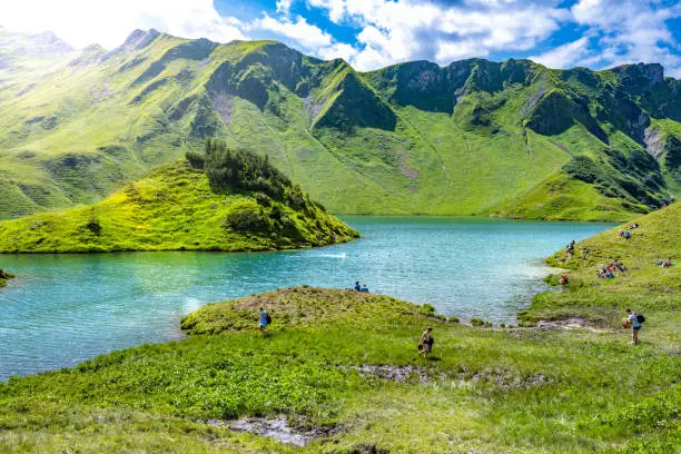 Description: Tourists enjoy beautiful turquoise mountain lake in the afternoon. Schrecksee, Hinterstein, Allgäu High Alps, Bavaria, Germany.