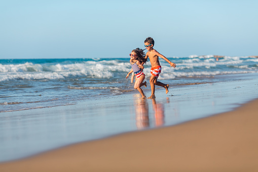 Girl and boy enjoys running on the beach on their summer vacation