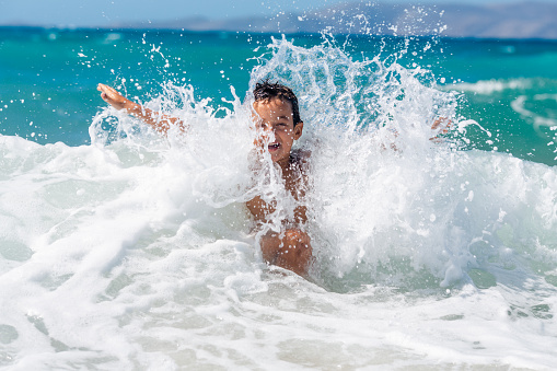 Boy having excitement in the sea playing with the waves