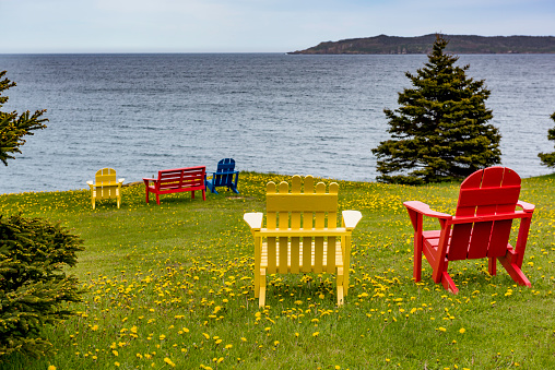 A traditional Adirondak outdoor chair on the porch of a brightly painted wooden house, typical to Eastern Canada. This one was photographed on Prince Edward Island.