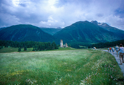 Tourists are walking on the Country road to Church of St. Gian, Celerina Schlarigna, Switzerland.