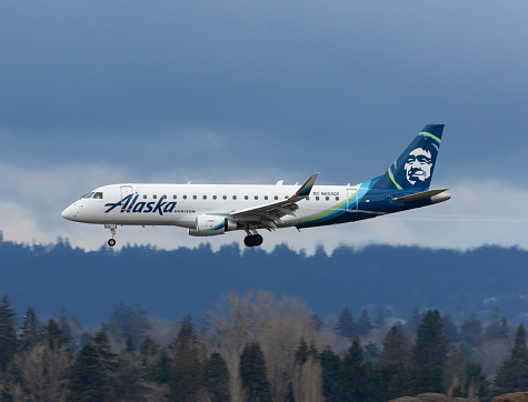 Portland, Oregon, USA - March 10, 2023:  A Horizon Air Embraer 175 landing at Portland International with condensation vortices coming off the wings.