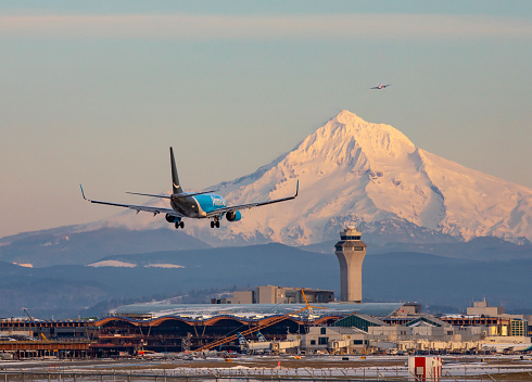Portland, Oregon, USA - February 25, 2023: An Amazon Prime 737 lands at a snow covered Portland International Airport with Mt Hood in the background.