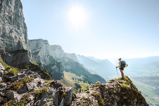 Description: A young sporty woman enjoys the  amazing view from a vantage point on churfürsten mountain range in the morning. Schnürliweg, Walensee, St. Gallen, Switzerland, Europe.