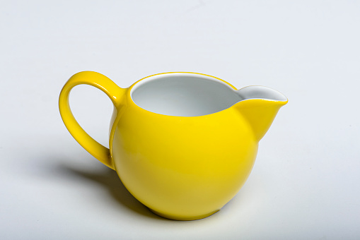 Beautiful bright yellow modern porcelain milk jug isolated on white background