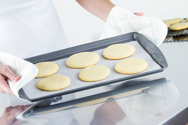Baking Sugar Cookies A chef holding a baking sheet with unbaked cookies. white sugar cookie stock pictures, royalty-free photos & images