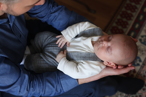 Newborn boy sleeping on his father's lap