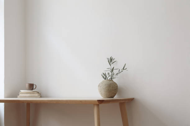 istock Elegant Mediterranean home design. Textured vase with olive tree branches, cup of coffee. Books on wooden table. Living room still life. Empty wall copy space. Modern interior, no people. Home office 1484653584