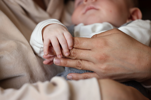 Newborn boy sleeping on his mother's lap