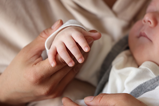 Newborn boy sleeping on his mother's lap