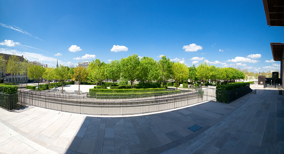 Breche Garden large panorama on a sunny day, trees, blue sky, modern building