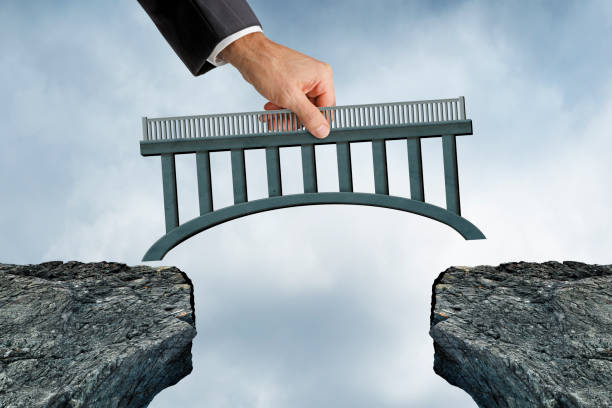 Man Placing Bridge Into Place A man palces a bridge into the space between two cliffs. bridge hand stock pictures, royalty-free photos & images