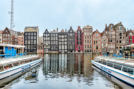 Amsterdam, Netherlands - March 28, 2023: Iconic houses along the canal across from the train station in Amsterdam