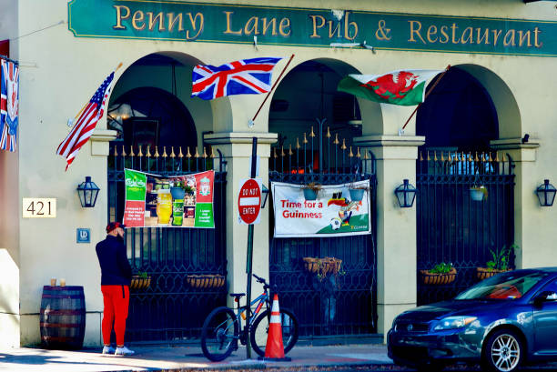 Richmond, Virginia, USA - November 202, 2022: A man talks on the phone outside the Penny Lane Pub & Restaurant in downtown Richmond on a windy afternoon.