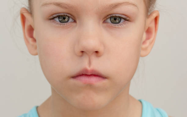 ernstes kindergesicht mit geschlossenen lippen abgeschnittener kopf kaukasisches kleines mädchen von 6 7 jahren auf grauem hintergrund - articulator stock-fotos und bilder