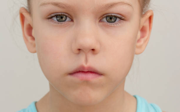 poważna twarz dziecka z przyciętymi ustami, przycięta głowa, kaukaska dziewczynka 6 7 lat na szarym tle - articulator zdjęcia i obrazy z banku zdjęć
