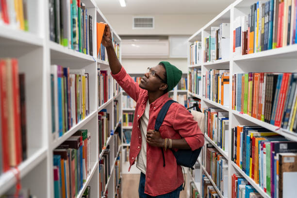 istock Nerd student african american man choosing book in university library taking it from shelf. 1484692852