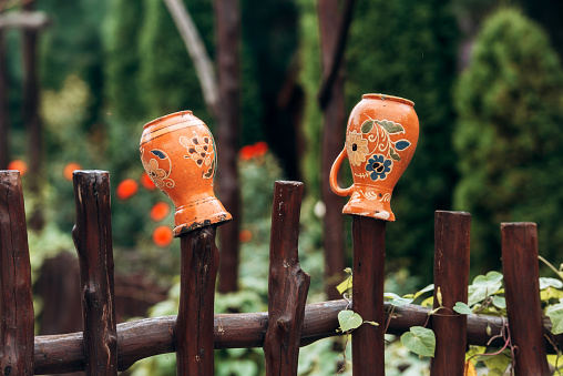 Two old jugs on the wood fence. Traditional ukrainian fence with clay pots