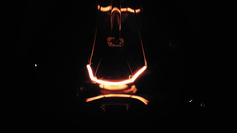 The Incandescent Bulb Turns On, and Off and Flickers on Black Background