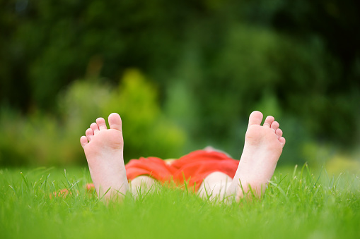 Children's feet on grass outdoors in summer park