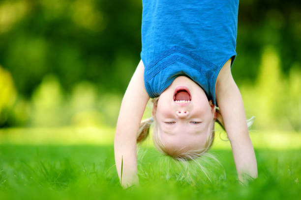 istock Happy young child playing head over heels on green grass 1484700207
