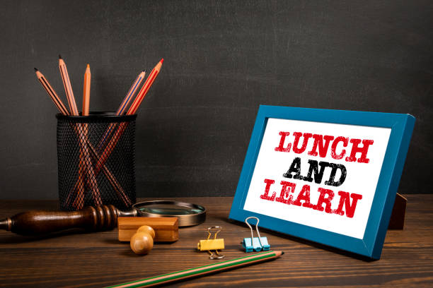 istock Lunch and Learn concept. Text in a picture frame on a wooden office table 1484708637